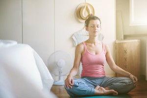 Mid adult woman in yoga lotus position in bedroom